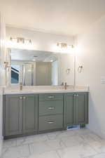 Full bathroom with double vanity, light marble finish flooring, and a shower stall