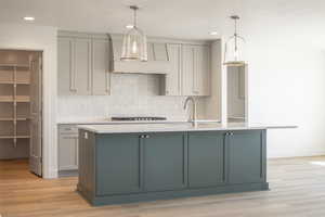 Kitchen featuring gray cabinetry, a kitchen island with sink, decorative light fixtures, decorative backsplash, and recessed lighting