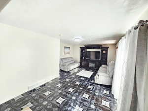 Living area with a textured ceiling and dark tile patterned flooring