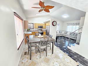 Dining area with lofted ceiling, light tile patterned floors, and a ceiling fan