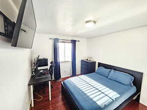 Bedroom featuring dark wood-type flooring, a desk, and a textured ceiling