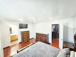 Bedroom with a spacious closet, dark wood-style floors, recessed lighting, and connected bathroom