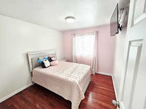 Bedroom with hardwood / wood-style floors and a textured ceiling
