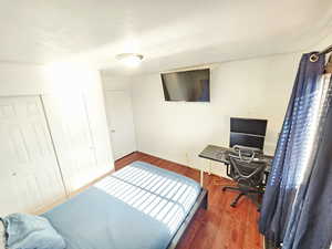 Bedroom featuring wood finished floors, an office area, and a closet
