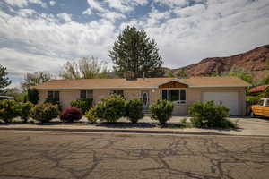 Ranch-style home with an attached garage, driveway, stucco siding, and a shingled roof
