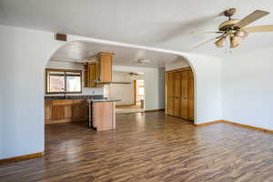 Kitchen with arched walkways, brown cabinetry, open floor plan, stainless steel range with electric stovetop, and a textured ceiling