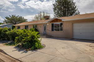 Ranch-style home featuring an attached garage, stucco siding, driveway, and roof with shingles