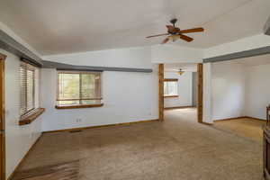 Carpeted empty room featuring lofted ceiling and ceiling fan