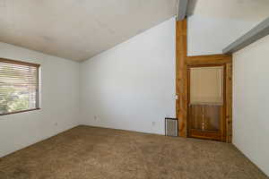 Empty room featuring carpet, lofted ceiling, and a textured ceiling