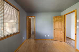 Unfurnished bedroom featuring hardwood / wood-style flooring and baseboards