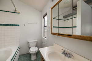 Bathroom with vanity, tile patterned flooring, lofted ceiling, and tiled shower / bath combo