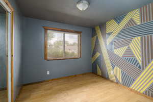 Spare room featuring light wood-style floors, wallpapered walls, and an accent wall