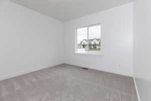 Carpeted spare room featuring baseboards