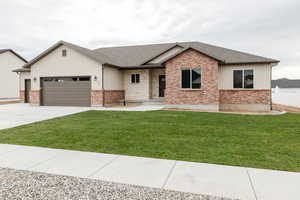 View of front facade with a shingled roof, an attached garage, concrete driveway, and a front lawn