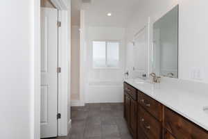 Bathroom featuring double vanity, a garden tub, dark tile patterned floors, and recessed lighting