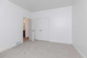 Unfurnished bedroom with light carpet and a closet