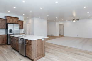 Kitchen with tasteful backsplash, appliances with stainless steel finishes, open floor plan, an island with sink, and recessed lighting