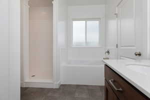 Bathroom with a bath, vanity, a shower stall, and dark tile patterned floors