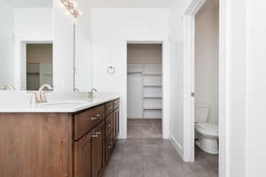 Bathroom with a walk in closet, double vanity, and light tile patterned floors