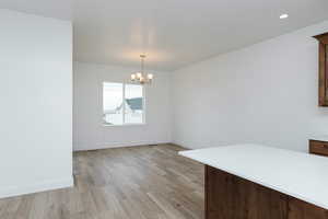 Unfurnished dining area featuring a chandelier and light wood finished floors