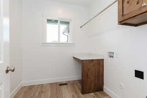 Laundry area with hookup for a washing machine, light wood-type flooring, cabinet space, and electric dryer hookup