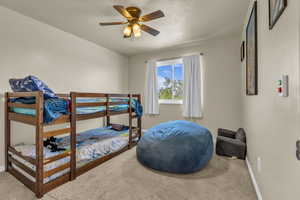 Bedroom featuring a ceiling fan, a textured ceiling, and carpet