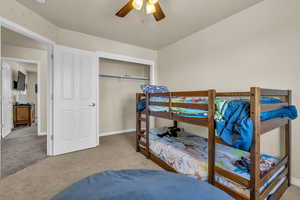 Bedroom featuring light carpet, a ceiling fan, and a closet