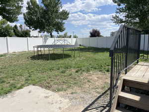 Fenced backyard featuring a trampoline