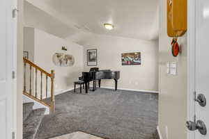 Carpeted entryway featuring vaulted ceiling, stairway, and a textured ceiling