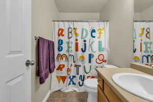 Bathroom with vanity, light tile patterned floors, a textured ceiling, and a shower with curtain