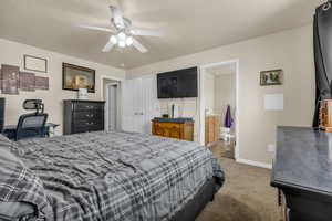 Bedroom with light colored carpet, ceiling fan, a textured ceiling, ensuite bath, and a closet