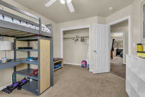 Bedroom with light carpet, a ceiling fan, and a closet