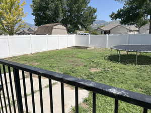Fenced backyard featuring a trampoline, a mountain view, a balcony, and a residential view