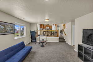 Living room with light colored carpet, a textured ceiling, and stairs