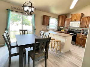 Dining space featuring vaulted ceiling, light wood-type flooring, and a chandelier