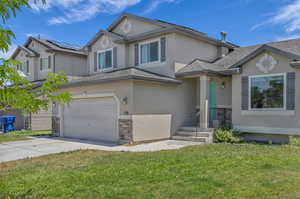 View of front of property featuring stucco siding, an attached garage, a front lawn, and roof with shingles
