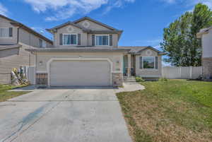 Traditional-style house with an attached garage, stucco siding, and concrete driveway