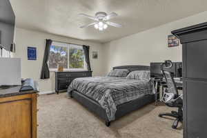 Bedroom featuring light carpet, a textured ceiling, ceiling fan, and an office area