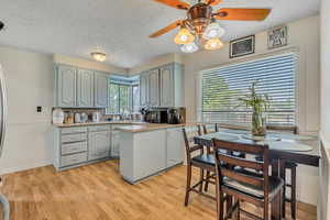 Kitchen featuring a textured ceiling, light countertops, a ceiling fan, light wood-style flooring, and a peninsula