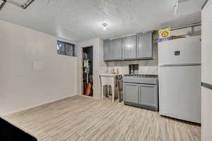 Kitchen with gray cabinets, freestanding refrigerator, a textured ceiling, and decorative backsplash