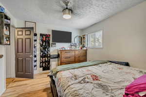 Bedroom featuring light wood-type flooring, a textured ceiling, and a closet