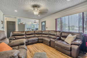 Living room with crown molding, wood finished floors, a textured ceiling, a ceiling fan, and recessed lighting
