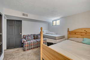 Bedroom featuring light carpet and a textured ceiling