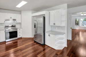 Kitchen with open shelves, tasteful backsplash, stainless steel appliances, and white cabinets