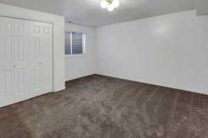 Unfurnished bedroom with dark carpet, a closet, and a textured ceiling
