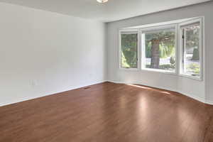 Unfurnished room featuring dark wood-type flooring and baseboards