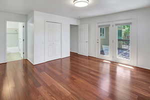 Unfurnished bedroom featuring wood-type flooring, access to outside, ensuite bathroom, and a closet