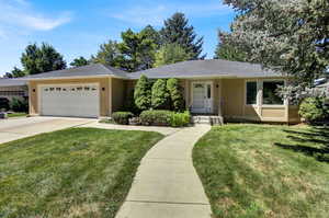 Ranch-style house with stucco siding, a front lawn, and an attached garage