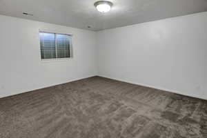 Unfurnished room featuring dark colored carpet and a textured ceiling
