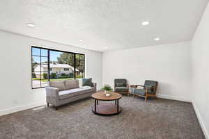 Carpeted living room featuring recessed lighting and a textured ceiling